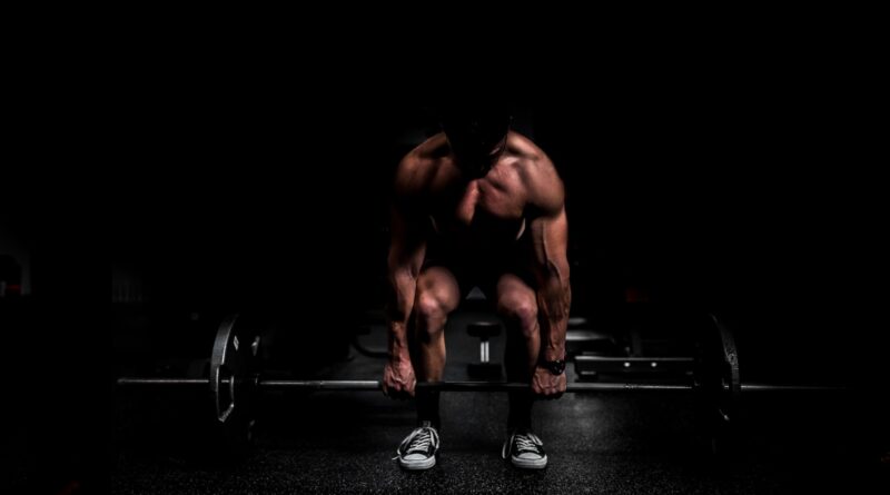 topless man in black shorts sitting on black and silver barbell