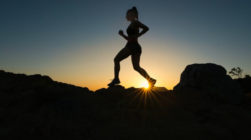 silhouette of man jumping on rocky mountain during sunset